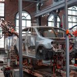 gray vehicle being fixed inside factory using robot machines