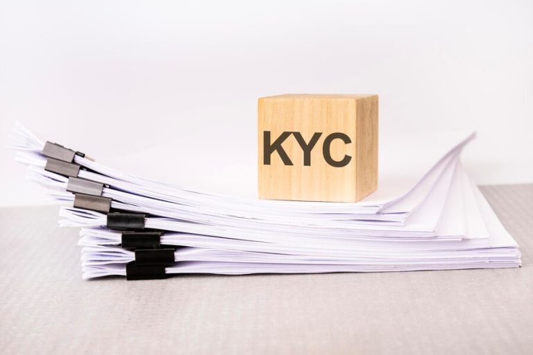wooden-cube-with-text-kyc-stack-documents-grey-table-white-background_384017-7468